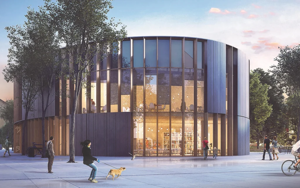 Wejście do biblioteki o zmierzchu — szklana, zaokrąglona fasada w pionowych drewnianych żebrach z widoczną w środku strefą z regałami na książki, spacerowicze i rowerzysta na placu.