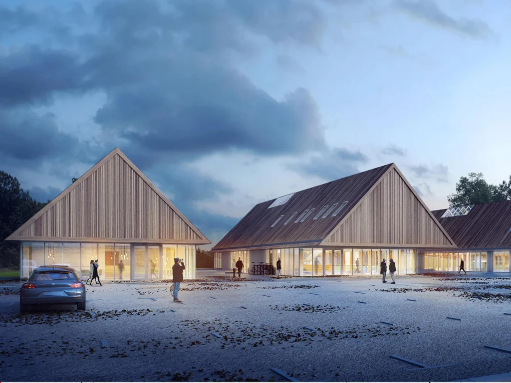 Wejście do pawilonów muzeum o zmierzchu — drewniane, oszalowane deskami elewacje szczytowe, oświetlone wnętrza widoczne przez przeszklone parterowe ściany i samochód na placu przed budynkiem.